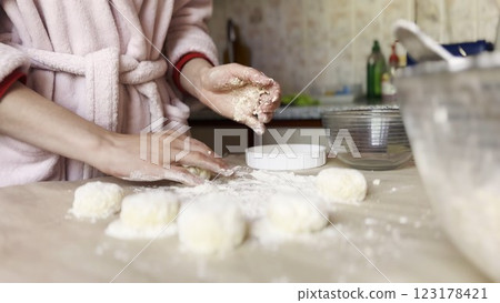 Female hands sculpting cottage cheese pancakes on cuisine table. Arms of young woman preparing tasty breakfast on desk. Process of making cheesecakes in home kitchen. Cooking healthy food concept 123178421