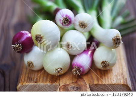 Bunch of fresh onions with greens on a wooden cutting board 123179240