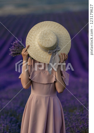 A woman wearing a hat and holding a bunch of lavender flowers 123179627