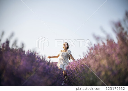 Lavender field happy girl in white dress with a scythe runs through a lilac field of lavender. Aromatherapy travel 123179632