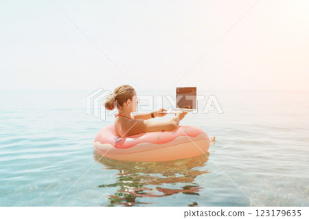 Woman laptop sea. Freelancer woman in sunglases floating on an inflatable big pink donut with a laptop in the sea. People summer vacation rest lifestyle concept Woman laptop sea. Freelancer woman in sunglases floating on an inflatable big pink donut with a laptop in the sea. People summer vacation rest lifestyle concept 123179635