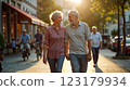 Happy European senior couple in love walking together in city streets on sunny summer evening 123179934