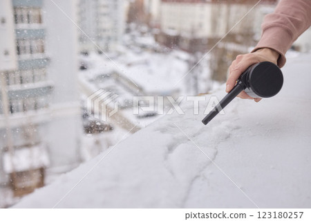 Utilizing a Snow Removal Tool on a Roof During the Winter Season for Safety and Maintenance 123180257