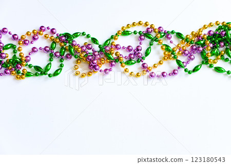 Mardi Gras background. Gold, green and purple beads on white background. Fat Tuesday symbol. 123180543
