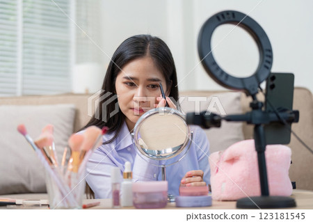 Asian woman perfecting eyebrow makeup in home studio Asian woman perfecting eyebrow makeup in home studio 123181545