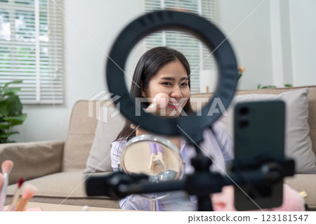 Asian woman smiling while using blush in home makeup routine Asian woman smiling while using blush in home makeup routine 123181547