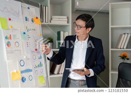 Elderly businessman presenting data analysis on a board in a modern office. Elderly businessman presenting data analysis on a board in a modern office. 123181550