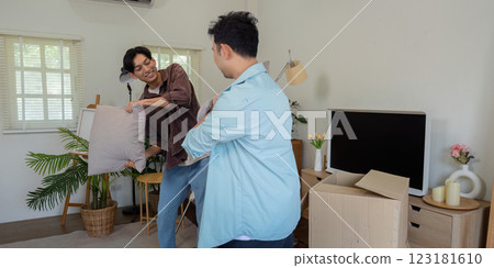 Gay couple enjoying a fun moment with pillow during moving process. Gay couple enjoying a fun moment with pillow during moving process. 123181610