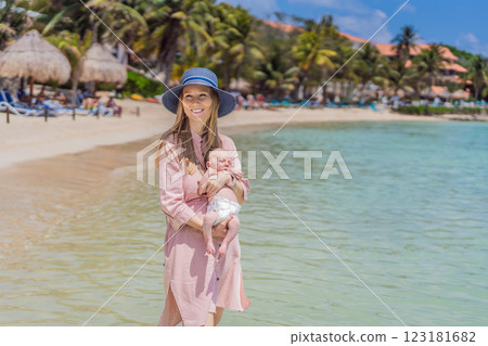 A mother introduces her newborn baby to the sea for the first time, holding her little one close as they experience the ocean breeze and the soothing sound of waves. A heartwarming moment of love 123181682