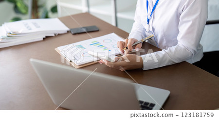 Accountant reviewing financial metrics and preparing reports using a laptop and clipboard. Accountant reviewing financial metrics and preparing reports using a laptop and clipboard. 123181759