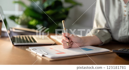 Woman analyzing financial documents while holding a pen, emphasizing financial planning. Woman analyzing financial documents while holding a pen, emphasizing financial planning. 123181781