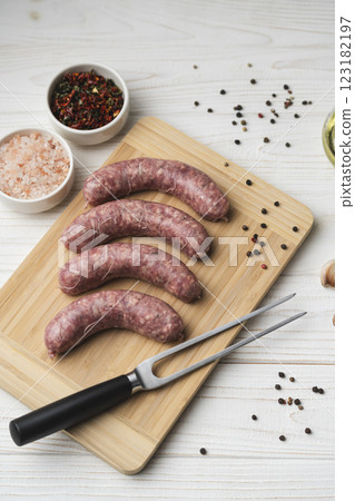 Uncooked grilled sausages on the wooden cutting board 123182197