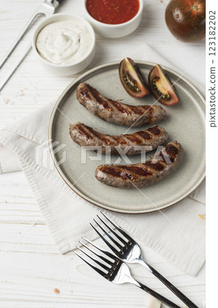 Ready to eat grilled sausages on the plate, white wooden background, close up Ready to eat grilled sausages on the plate, white wooden background, close up 123182202