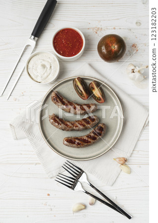 Ready to eat grilled sausages on the plate, white wooden background, close up 123182203