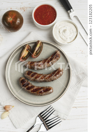 Ready to eat grilled sausages on the plate, white wooden background, close up 123182205