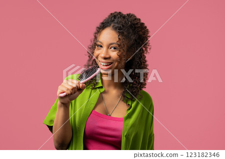 African teenager girl singing, dancing with hairbrush as microphone on pink African teenager girl singing, dancing with hairbrush as microphone on pink 123182346