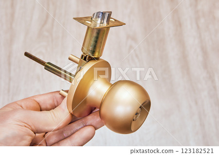 Tubular door latch assembly is being held, highlighting brass components and intricate, exposed mechanism. Tubular door latch assembly is being held, highlighting brass components and intricate, exposed mechanism. 123182521
