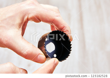 Hand holding circular hole saw with serrated cutting edges. 123182528