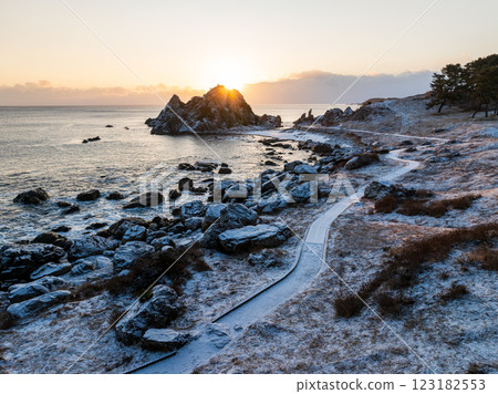 青森縣中須賀海岸的白雪皚皚的鳥瞰圖，沐浴在朝陽的橙色光芒中；八戶市種差海岸 123182553