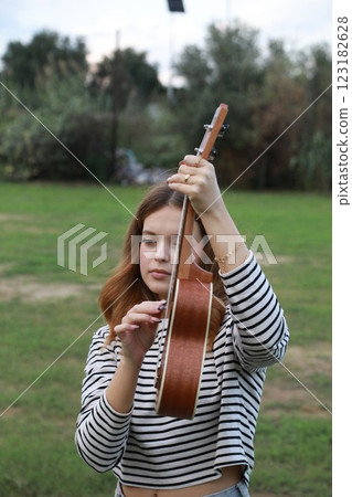 Girl Practices With Ukulele Musical Instrument In The Countryside During A Break 123182628