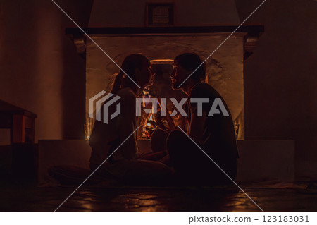 Family bonding by the fireplace during cozy winter evening. Warm and peaceful family moment indoors. Togetherness, love, and relaxation concept. A warm and inviting scene featuring a lit fireplace 123183031