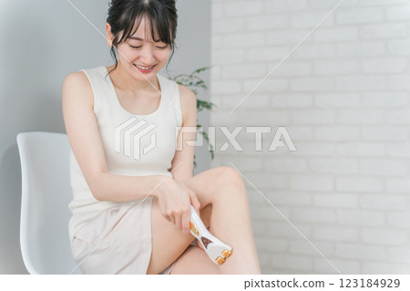 Asian woman using a beauty appliance roller to remove waste from her calves Asian woman using a beauty appliance roller to remove waste from her calves 123184929