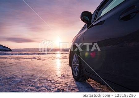 Winter sunset over Baikal Lake with a car parked near the frozen shoreline showcasing natural beauty and serene landscapes 123185280