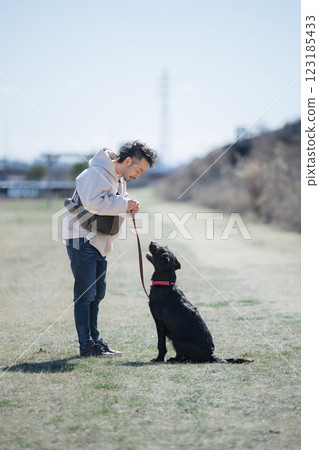 Image of a man training a dog outdoors, gazing at the dog 123185433