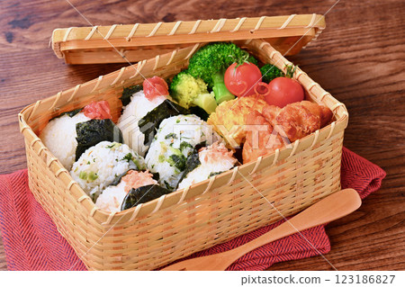 飯糰飯盒。鮭魚、野澤魚小沙丁魚、醃梅子。炸雞、蛋捲、綠花椰菜和小聖女果。 123186827