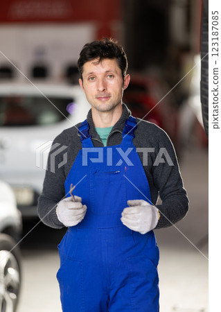 Adult man mechanic in uniform posing in car service station Adult man mechanic in uniform posing in car service station 123187085
