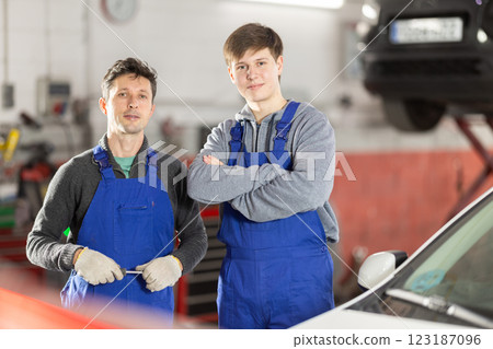 Portrait of two professional auto mechanics in uniform in the interior of car service 123187096