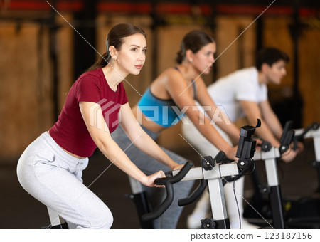 Focused girl works out with exercise bicycle during class at fitness club 123187156