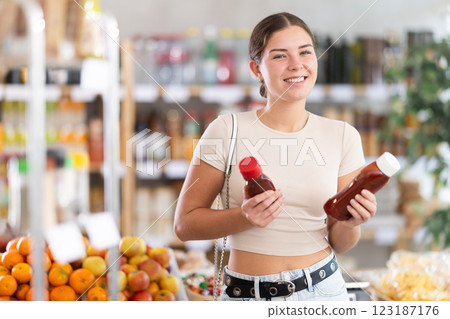 Young woman choosing ketchup in grocery store 123187176