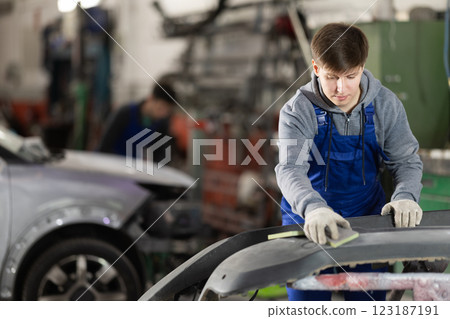 Young man auto mechanic handle polishes body parts Young man auto mechanic handle polishes body parts 123187191