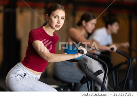 Focused girl works out with airbike during class at fitness club Focused girl works out with airbike during class at fitness club 123187193