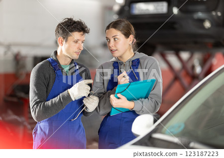 Young woman supervisor manager of car repair station with papers listens to male master 123187223