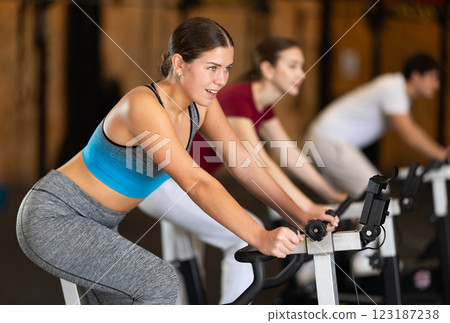 Focused girl works out with exercise bicycle during class at fitness club 123187238