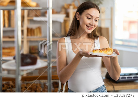Satisfied female customer holding sweet pie in bakery interior Satisfied female customer holding sweet pie in bakery interior 123187272