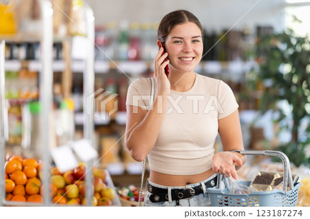 Woman with phone in hands walks around store, call to friend, speak with mother 123187274