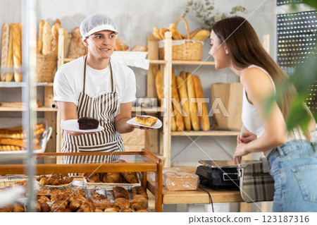 Salesman giving pastry to female buyer in bakery 123187316