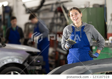 Service station young woman employee works in repair box, department 123187319