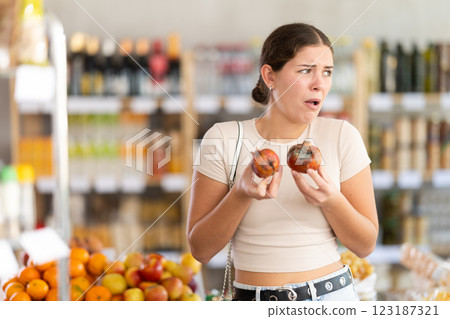 Young woman with rotten pomegranates in grocery store Young woman with rotten pomegranates in grocery store 123187321