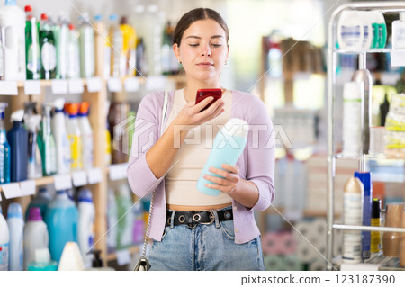 Young woman scanning QR-code on shampoo in department store Young woman scanning QR-code on shampoo in department store 123187390