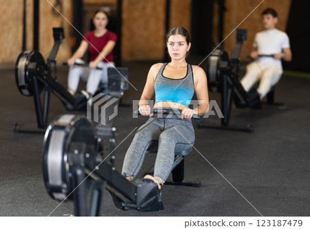 Focused girl works out with rowing machine during class at fitness club 123187479