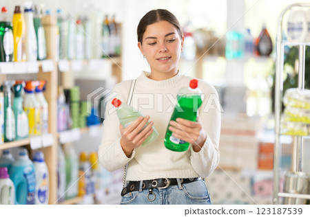Girl housewife in household store examines package, chooses dishwashing 123187539
