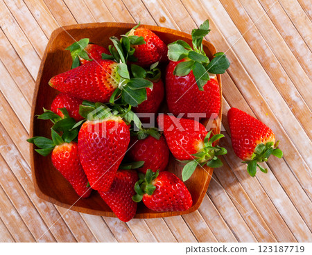 There is plate with pile of ripe strawberries on table 123187719