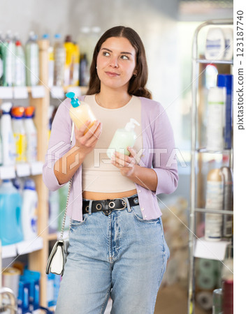 Young woman buyer chooses liquid soap in store Young woman buyer chooses liquid soap in store 123187740