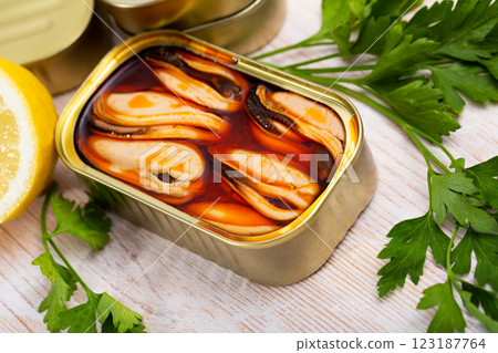 Sea pickled mussels in open tin can served with greens and lemon 123187764