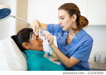 Female cosmetologist marking skin of hispanic with white pencil Female cosmetologist marking skin of hispanic with white pencil 123187856