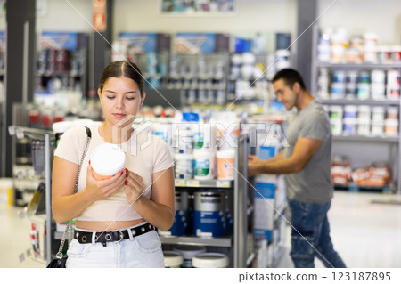 Positive girl planning to make house renovation, choosing paints in store 123187895